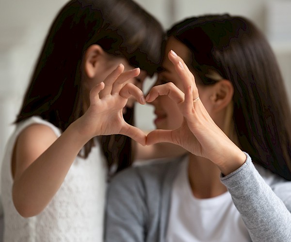 A girl and woman's hands forming a heart shape together