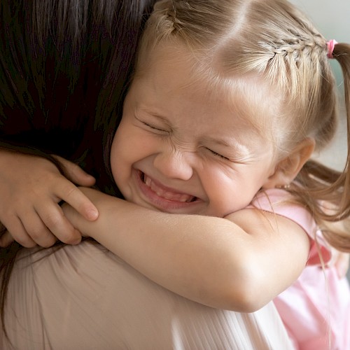 Very happy young girl seen over the shoulder of a woman