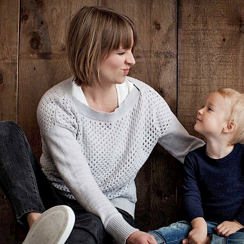Smiling young boy looking up at woman making silly faces