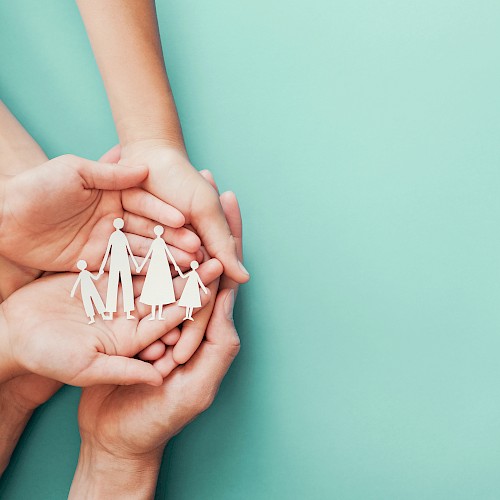 Family group of hands cradling a cut out family silouette from white paper
